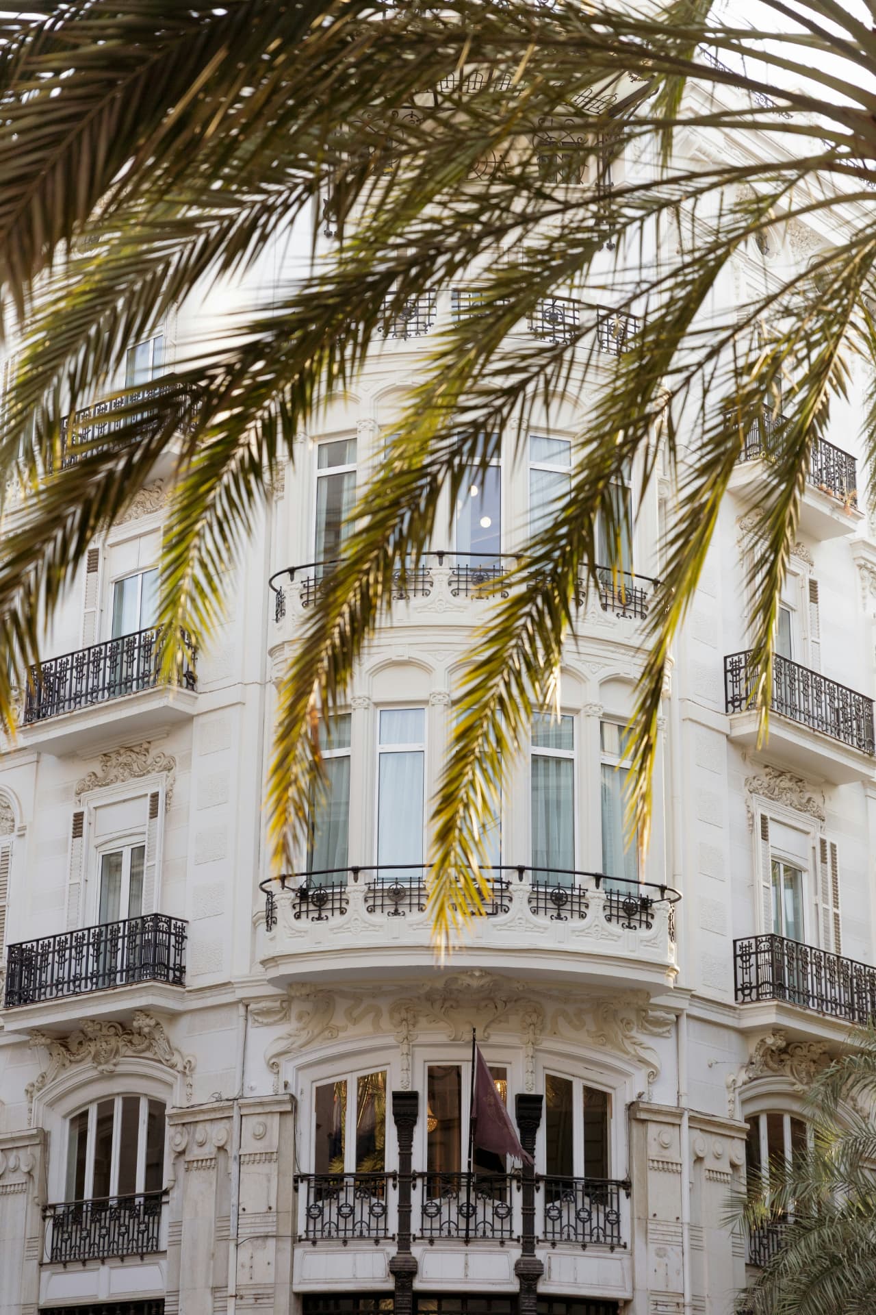 Fachada mediterránea con balcones y palmeras en Valencia